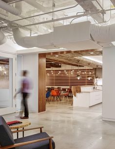 a blurry image of a person walking through an office building with chairs and desks