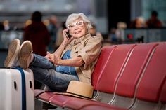 an older woman sitting on a bench with her feet up to the ground while talking on a cell phone