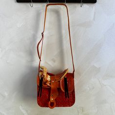 a brown leather purse hanging from a hook on a white wall next to a coat rack