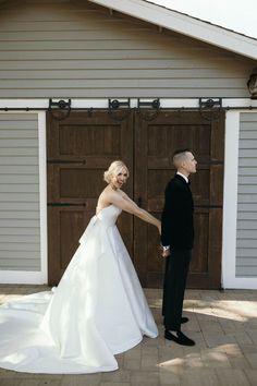 a bride and groom holding hands in front of a garage door