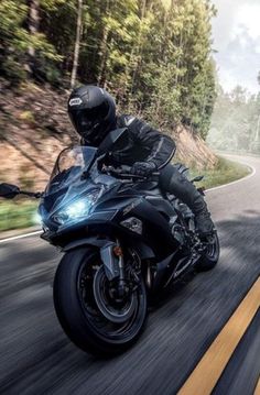 a person riding a motorcycle on a road with trees in the backgrouund