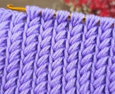 a close up view of a purple knitted blanket with yellow pins in the middle