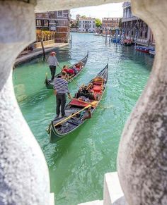 two gondolas in the water with people standing on one side and another boat at the other