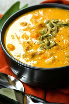 a black bowl filled with soup and topped with pumpkin seeds