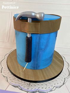 a blue and brown hat with a hammer sticking out of it's side on a plate