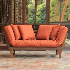 an orange couch sitting on top of a brick floor next to a wooden frame structure