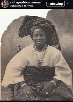 an old photo of a woman sitting in a chair with a headdress on