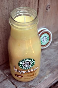 a glass jar filled with liquid sitting on top of a wooden table next to a cup