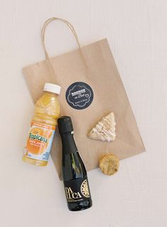 a bottle of orange juice and some cookies on a table next to a paper bag