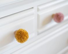 a close up of a drawer with two knobs on it and one has a fuzzy ball in the middle