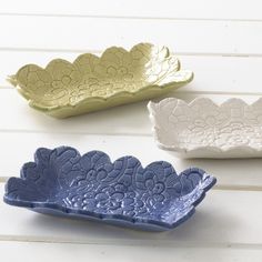 three ceramic dishes sitting on top of a white table