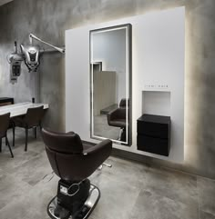 a hair salon with chairs, mirrors and lights on the wall in front of it