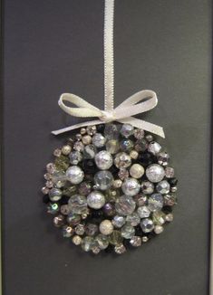 a christmas ornament hanging on a wall with a ribbon and bow around it