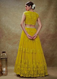 Elevate your festive wardrobe with the exquisite Yellow Floral Embroidered Lehenga set—a perfect blend of tradition and contemporary elegance. Made from soft net fabric, the yellow lehenga features flowy gathers at the waist, beautifully adorned with scattered floral embroidery in sequins and threadwork, creating a mesmerizing visual appeal. Paired with a matching cap-sleeved blouse that showcases intricate embroidery, a sheer back, and a flattering sweetheart neckline, this ensemble adds a touch of modern sophistication. The look is completed with a delicate rose pink net dupatta, embellished with embroidered buttis and finished with elegant cutwork lace. Enhanced with cancan for added volume and convenient pockets, this lehenga set is ideal for Haldi, Mehndi, Sangeet, or as wedding guest Thread Work Lehenga, Bridal Crop Top, Kaftan Kurta, Cutwork Lace, Kurta Lehenga, Prince Coat, Net Skirt, Waistcoat Woman, Yellow Lehenga