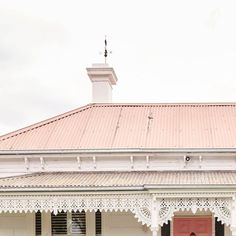 a woman standing in front of a red door on top of a white brick building