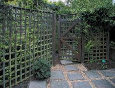 an open gate in the middle of a garden with stone pavers and plants around it