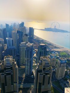 an aerial view of a city with tall buildings and ferris wheel in the distance,