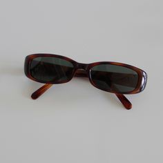 These slim rectangle sunglasses are your everyday classic. Featuring a red tortoise frame with smoke lens. This style is unisex. True genuine vintage sunglasses from the 90s.  - 400 uv  - new vintage from the 90s - includes sunglasses pouch  Measurements: Cheap Rectangular Tortoiseshell Sunglasses, Vintage Sunglasses Outfit, Vintage Sunglasses Aesthetic, Thrift Manifestation, Random Accessories, Narrow Sunglasses, 90s Glasses, Autumn 23, 90s Sunglasses