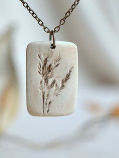 a white square pendant with a plant on it