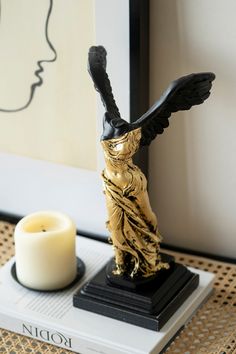 a candle and statue on a table next to a framed photograph with a woman's face in the background