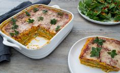 a casserole dish with meat and vegetables in it on a table next to plates