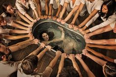 a group of people standing around a hot tub in the middle of a floored room