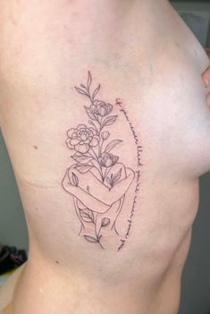 a woman's breast with flowers and writing on the side by tattoo artist person