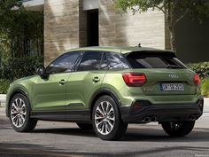 the rear end of a green audi suv parked in front of a building with its trunk open