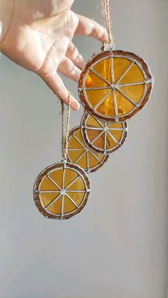 a hand holding three orange slices hanging from strings