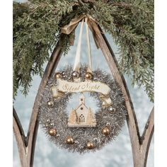 a christmas wreath hanging from the side of a wooden arch with a church on it