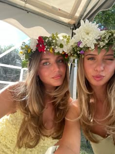 two beautiful young women sitting next to each other wearing flowers in their hair and wreaths