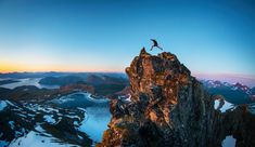 a man standing on the top of a mountain with his feet in the air above him