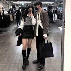 two people standing next to each other in a clothing store