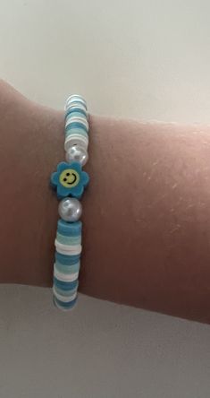 a woman's arm wearing a bracelet with a smiley face beaded on it