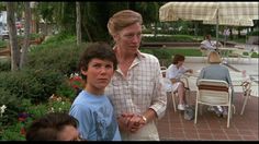 a woman standing next to two boys in front of an outdoor dining area with tables and umbrellas