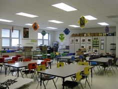 a classroom filled with lots of desks covered in paper kites hanging from the ceiling