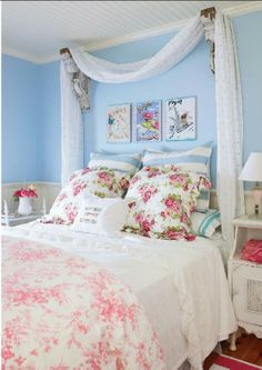 a bedroom with blue walls and white bedding, pink flowers on the comforter