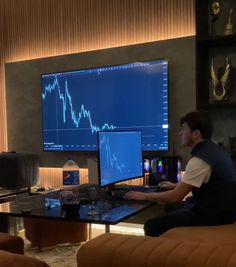 a man sitting at a desk in front of a computer monitor with a stock chart on it