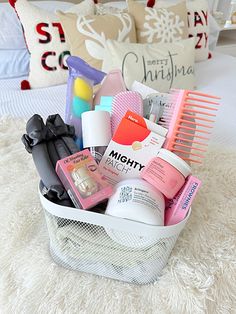 a white basket filled with lots of beauty products on top of a bed next to pillows