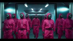 a group of people in pink suits and gas masks walk through a hallway with mirrors