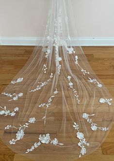 a veil with white flowers on it is sitting on the floor in front of a wall