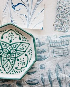 a green and white plate sitting on top of a table next to some papers with designs