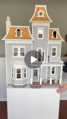 a woman is holding up a doll house