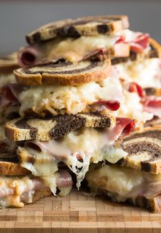 a pile of sandwiches sitting on top of a wooden cutting board