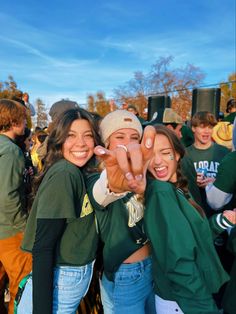 two girls are making the peace sign with their hands while standing in front of a group of people