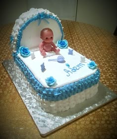 a baby's first birthday cake with blue icing and flowers on it, sitting on a table