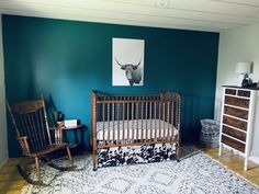 a baby's crib and rocking chair in a room with blue walls