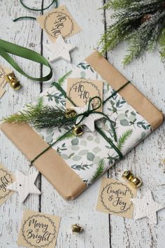 a wrapped present sitting on top of a wooden table next to christmas ornaments and tags