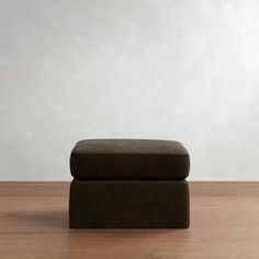 a footstool sitting on top of a wooden floor next to a white wall