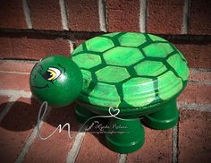 a green turtle statue sitting on top of a brick wall